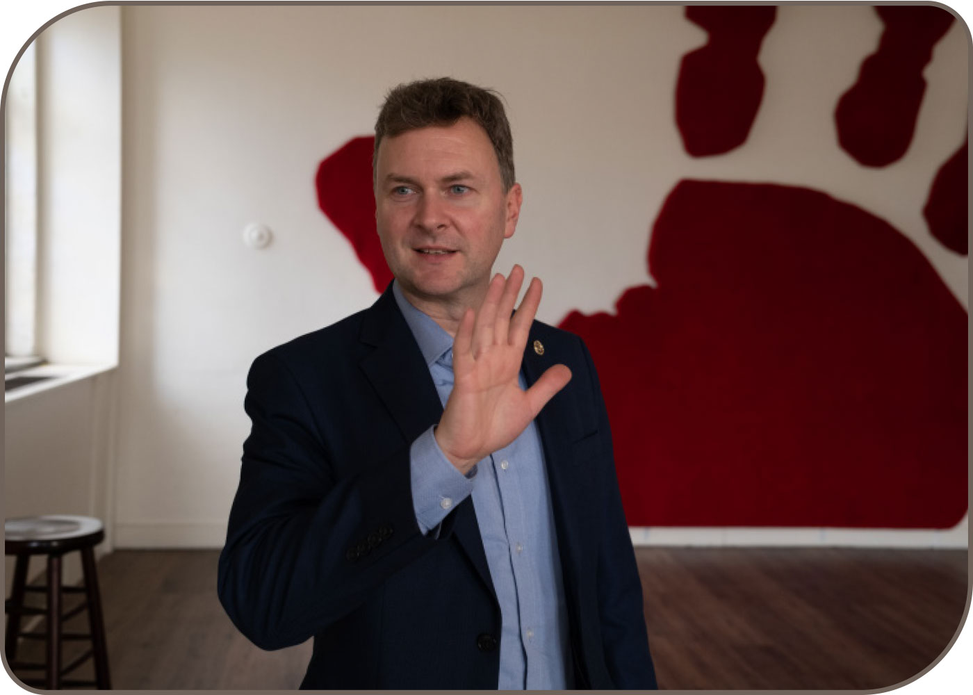 crawl space eviction improvisational actor holds his hand up in front of the hand print mural